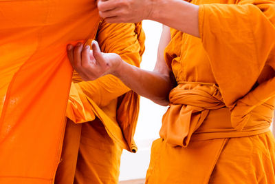Midsection of monks holding fabric while standing outdoors