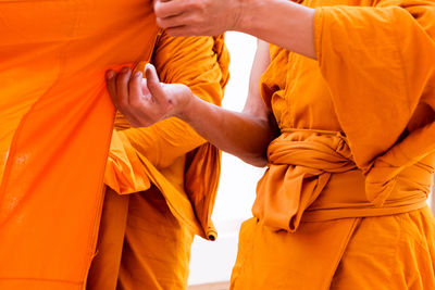 Midsection of couple holding yellow while standing against orange