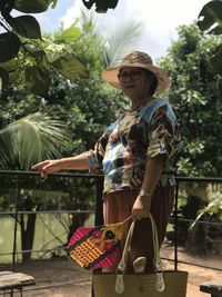 Woman holding umbrella against plants