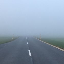 Empty road by fog against sky