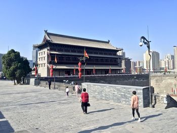 Rear view of people walking on street against clear sky