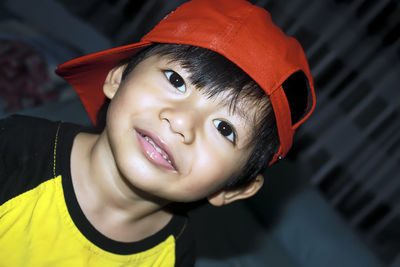 Close-up portrait of boy wearing red cap in darkroom