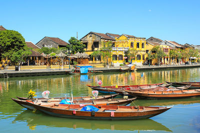 Boats moored in lake by buildings against clear sky