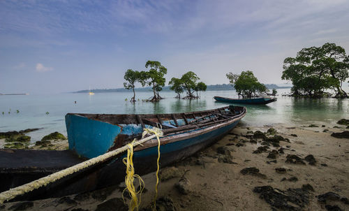 Boat moored on beach against sky