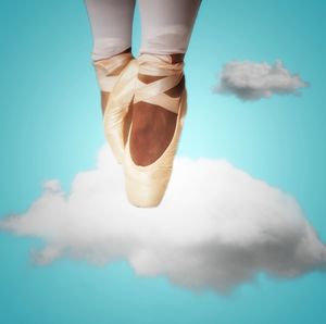 Digital composite image of ballet dancer dancing on cloud against blue background