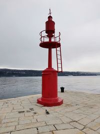 Lighthouse by sea against sky