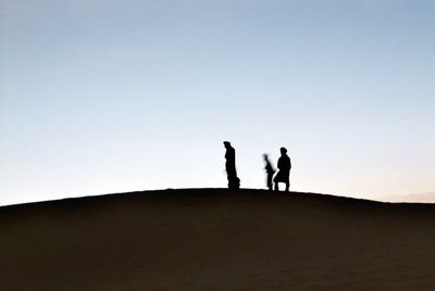 Silhouette people standing on land against clear sky