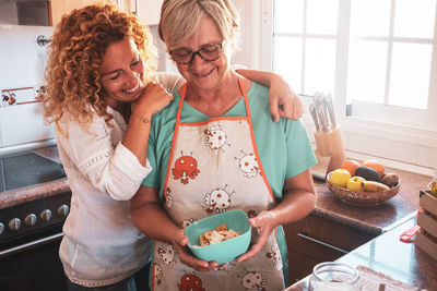 Smiling mother and daughter preparing food in kitchen