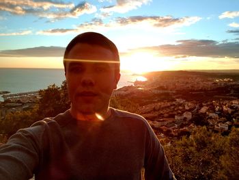 Portrait of man standing by sea against sky during sunset