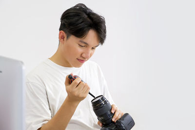 Mid adult man using smart phone against white background