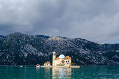Buildings at waterfront against cloudy sky