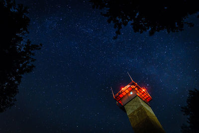 Low angle view of illuminated tower against star field