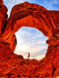 Woman standing on rock formation against sky