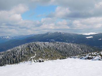 Scenic view of snow-covered mountains against cloudy sky