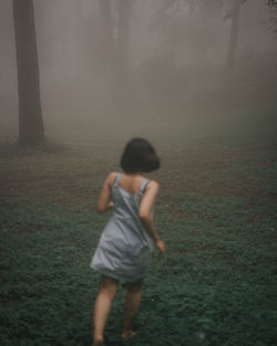 Rear view of woman running on field