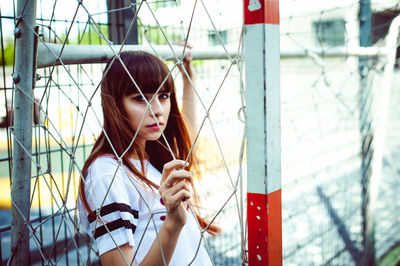 Portrait of young woman standing in goal post