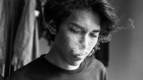 Close-up of young man smoking at home