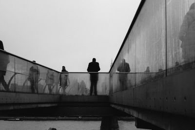 Man and woman walking on bridge against clear sky