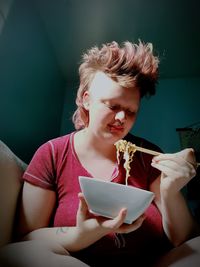 Young woman eating noodles at home