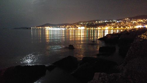 Silhouette of people in sea against sky at night