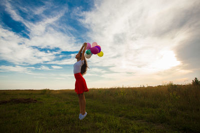 Side view of woman with balloon on field