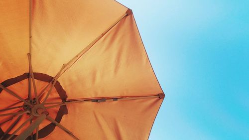 Low angle view of parasol against clear blue sky