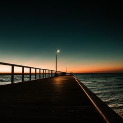 Pier over sea against sky during sunset