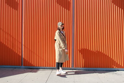 Full length of smiling woman standing on footpath