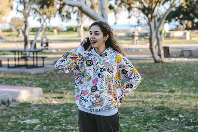 Teenager girl talking on phone while looking away while standing in park