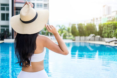 Rear view of woman standing by swimming pool