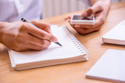 Midsection of man using mobile phone on table