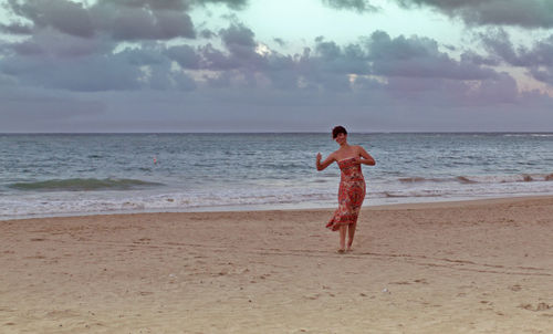 Full length of young woman standing on beach