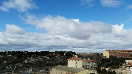 Buildings in town against cloudy sky