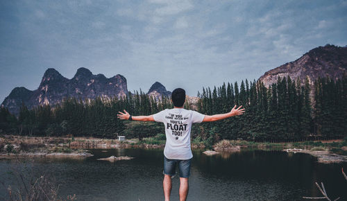 Rear view of man standing by mountain against sky