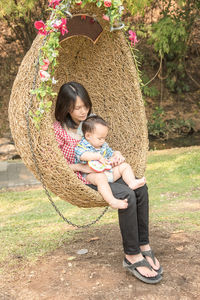 Full length of mother with son sitting on swing outdoors