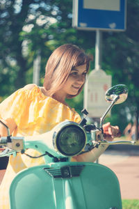 Smiling young woman sitting on motor scooter
