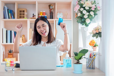 Young woman using phone while sitting on table at home