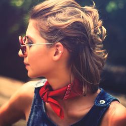 Close-up of young woman wearing sunglasses while sitting outdoors