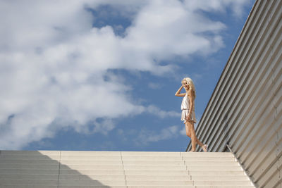 Woman standing by staircase against sky