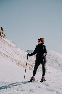 Full length of young man skiing on snow covered field