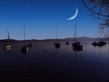 Sailboats in lake against sky at night