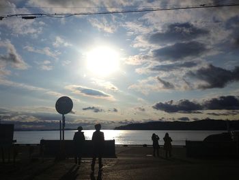 Silhouette people by sea against sky during sunset