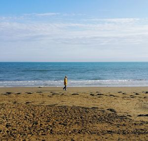 Senior man walking on beach against sky