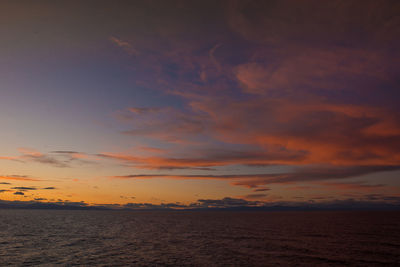 Scenic view of sea against dramatic sky during sunset