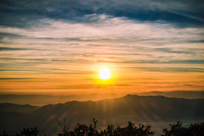 Scenic view of silhouette mountains against orange sky