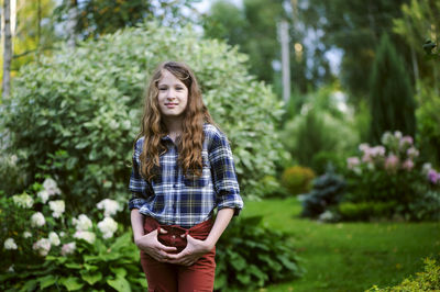 Portrait of young woman standing against plants
