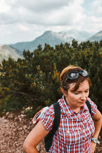 Woman with backpack hiking in a mountains, actively spending summer vacation, having break