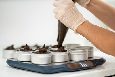 Close-up of hand piping cream in tins