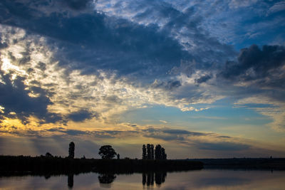 Silhouette trees by lake against sky during sunset