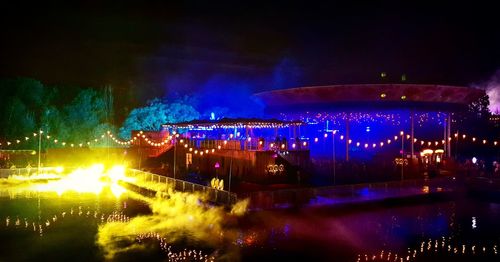 Illuminated fountain in city against sky at night